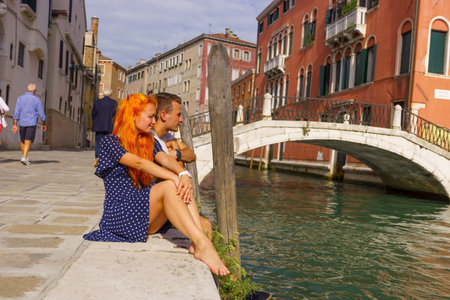 Young couple sitting in the border of canal in Venice.の写真素材