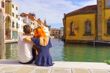 Young couple sitting in the border of canal in Venice.の写真素材