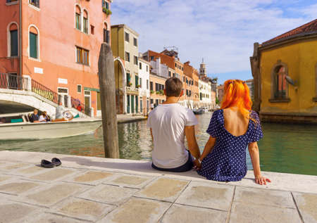 Young couple sitting in the border of canal in Venice.の写真素材