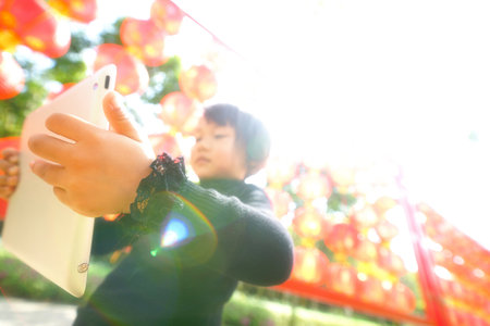 Outdoor portrait of cute small asian girl with tabletの写真素材
