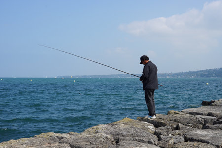GENEVA - SEP 11: man fishing at Geneva lake on September 11, 2014 in Geneva, Switzerland. Geneva is the second most populous city in Switzerland and is the most populous city of Romandy, the French-speaking part of Switzerlandのeditorial素材