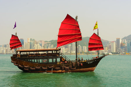 HONG KONG - APRIL 16, 2015: sailboat across Victoria Harbour. Victoria Harbour is a natural landform harbour situated between Hong Kong Island and Kowloon in Hong Kong.のeditorial素材