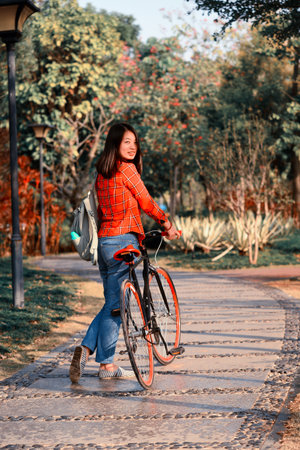 Pretty young chinese woman in the park walking with bicycleの写真素材