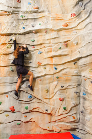 Businesswoman climbing on man-made cliff in the sport centreの写真素材