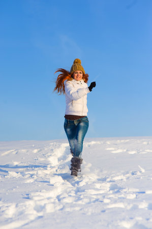 Pretty young woman with red hair take a fun on the snow fieldの写真素材