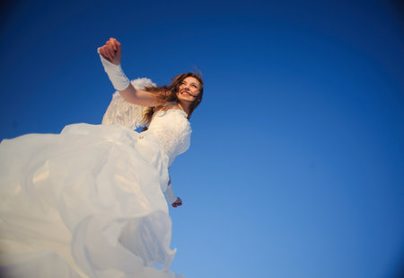 Beautiful young woman in wedding dress walking on snow fieldの写真素材