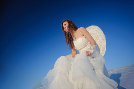 Beautiful young woman in wedding dress walking on snow fieldの写真素材