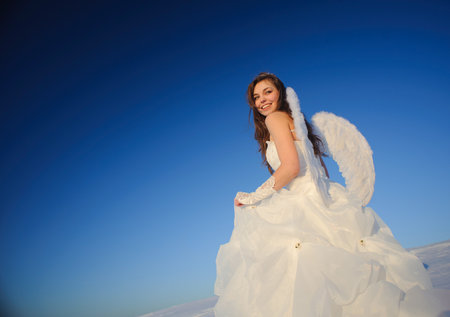 Beautiful young woman in wedding dress walking on snow fieldの写真素材