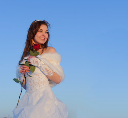 Beautiful young woman in wedding dress walking on snow fieldの写真素材