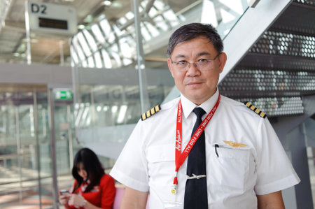 BANGKOK - OCT 27: Airasia pilot posing in Bangkok Airport on October 27, 2011 in Bangkok, Thailand. AirAsia Berhad is a Malaysian low-cost airline headquartered in Kuala Lumpur, Malaysiaのeditorial素材
