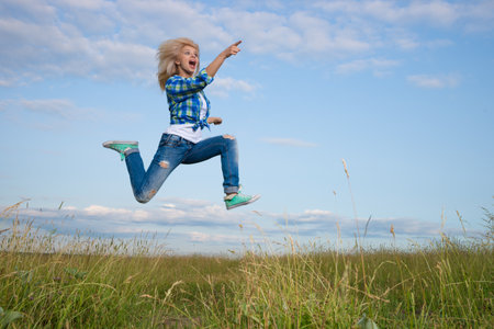 Professional gymnast woman jump in green grass fieldの写真素材