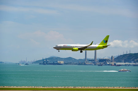HONG KONG - JUNE 04, 2015: Jin Air aircraft landing at Hong Kong airport. Jin Air Co. Ltd is a low cost airline originating from South Korea, and a wholly owned subsidiary of Korean Air.のeditorial素材