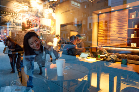 NEW YORK - CIRCA MARCH 2016: woman in Starbucks Cafe. Starbucks Corporation is an American global...