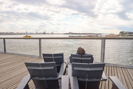 NEW YORK - MARCH 17, 2016: man sit in the armchair at Pier 15 at daytime. Pier 15 is located east of...