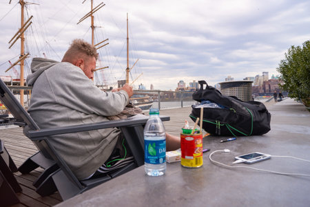 NEW YORK - MARCH 17, 2016: man sit in the armchair at Pier 15 at daytime. Pier 15 is located east of...