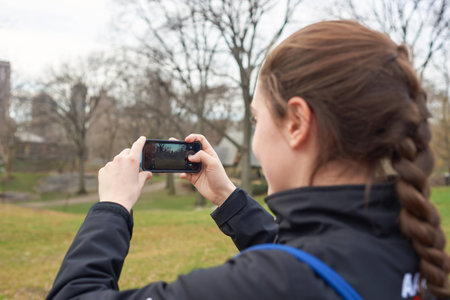 NEW YORK - CIRCA MARCH, 2016: young woman taking photo in Central Park. Central Park is an urban park in middle-upper Manhattan, within New York City.のeditorial素材