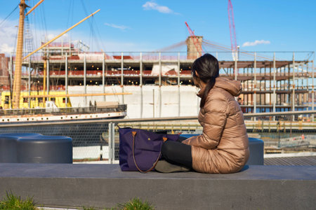 NEW YORK - MARCH 17, 2016: woman take a rest at Pier 15 at daytime. Pier 15 is located east of South Street and FDR Drive in Lower Manhattan, New York City.のeditorial素材