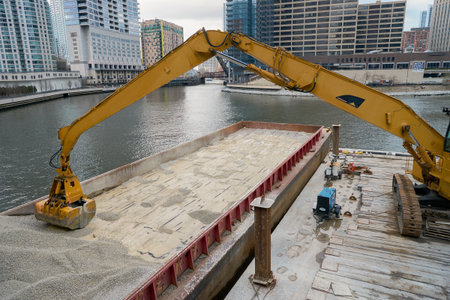 CHICAGO, IL - MARCH 31, 2016: Caterpillar excavator transferring gravel from barge in Chicago.  Chicago is the third most populous city in the United States.のeditorial素材