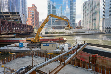 CHICAGO, IL - MARCH 31, 2016: Caterpillar excavator transferring gravel from barge in Chicago. ...