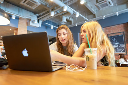 MOSCOW, RUSSIA- AUGUST 24, 2016: indoor portrait of two women at Starbucks coffee shop. Starbucks Corporation is an American coffee company and coffeehouse chain.のeditorial素材