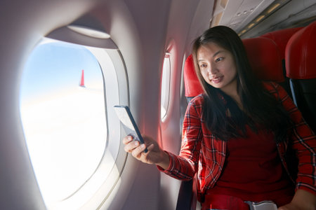 Young woman with smartphone inside of a single-aisle aircraft.の写真素材