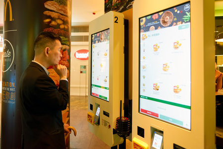 HONG KONG - CIRCA NOVEMBER, 2016: a man use a Mcdonald's ordering kiosks in Hong Kong. McDonald's is an American hamburger and fast food restaurant chain.のeditorial素材