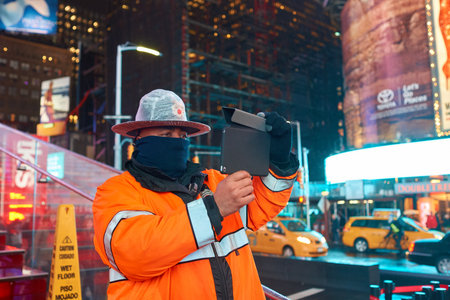 NEW YORK, NY - MARCH 14, 2016: a public safety officer taking photo in Times Square. Times Square is a major commercial intersection and neighborhood in the Midtown Manhattan section of New York City.のeditorial素材
