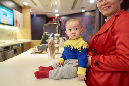 SHENZHEN, CHINA - CIRCA DECEMBER, 2016: woman with baby at McCafe in Shenzhen. McCafe is a coffee-house-style food and drink chain, owned by McDonald's.のeditorial素材