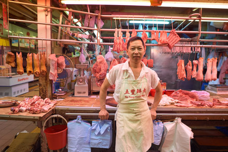 HONG KONG - OCTOBER 25, 2015: vendor and his meat stall in a market at Kennedy Town. Kennedy Town is at the western end of Sai Wan on Hong Kong Islandのeditorial素材