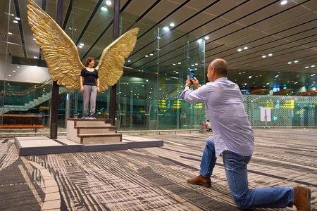 SINGAPORE - CIRCA AUGUST, 2016: man taking photo of woman with Wings of Mexico sculpture at...