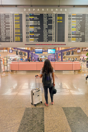 SINGAPORE - CIRCA AUGUST, 2016:  woman looking at timetable departure board in Singapore Changi Airport Terminal 2.のeditorial素材