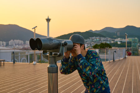 BUSAN, SOUTH KOREA - CIRCA MAY, 2017: man look in binocular telescope at observation area on the top...