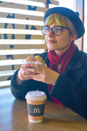 KALININGRAD, RUSSIA - CIRCA APRIL, 2018: caucasian woman eats at McDonald's restaurant in Kaliningrad.のeditorial素材