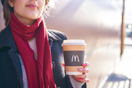 KALININGRAD, RUSSIA - CIRCA APRIL, 2018:  young woman with a cup of coffee from McDonald's in...