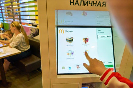 SYKTYVKAR, RUSSIA - CIRCA JULY, 2018: woman use self ordering kiosk in McDonald's