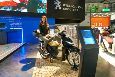 MILAN, ITALY - NOVEMBER 11, 2017: a model poses with a scooter for the visitors during the EICMA...