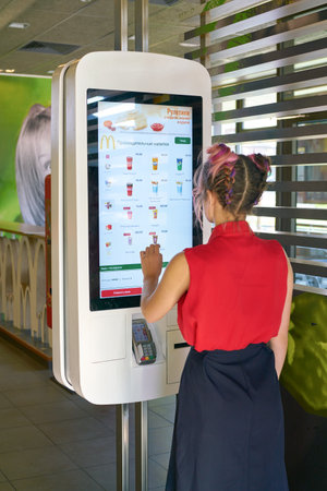 KALININGRAD, RUSSIA - CIRCA SEPTEMBER, 2018: woman use self ordering kiosk in McDonald's restaurant....
