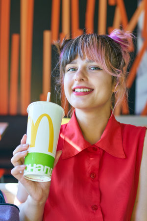 KALININGRAD, RUSSIA - CIRCA SEPTEMBER, 2018: indoor portrait of young beautiful woman with paper cup...