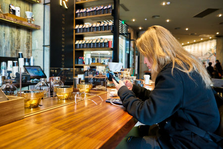 SHENZHEN, CHINA - CIRCA FEBRUARY,  2019: woman with smartphone sit at Starbucks in Shenzhen.のeditorial素材
