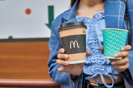 KALININGRAD, RUSSIA - CIRCA JULY, 2022: teenager with paper cups from McDonald's and fast food restaurant Vkusno I Tochka, Russian fast food chain mostly based in former McDonald's restaurants.のeditorial素材