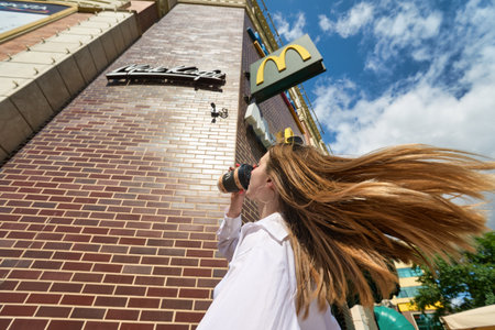 KALININGRAD, RUSSIA - CIRCA JULY, 2022: woman with paper cup against the background of McDonald's restaurant, closed after sanctions were imposed.のeditorial素材