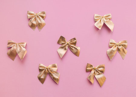 Gold bows Top view photo in minimal style Pattern with decorative gift bows on pink backgroundの写真素材