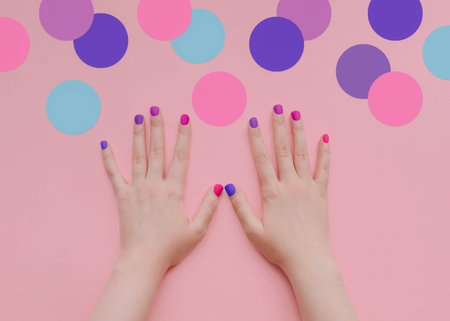 Hands of young woman on pink background with big multicolored confettiの写真素材