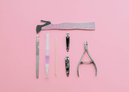Orange stick, nail file, lavender oil, metal tweezers, and wire cutters on pink backgroundの写真素材