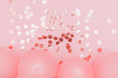 Holiday decoration. Flat lay photo for posters and banners. Glowing confetti and pink balloons on pink backdropの写真素材