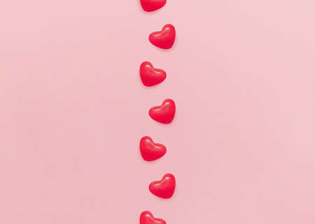 love sign. Flat lay photo in minimal style. Sugar candies in heart shapes on pink pastel backgroundの写真素材