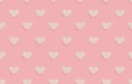 Love sign seamless pattern. top view photo. Cute texture with white candies in a heart shape on pastel pink backdropの写真素材