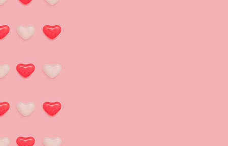 Love theme design template with copy space. White and red heart-shaped candies on pink background