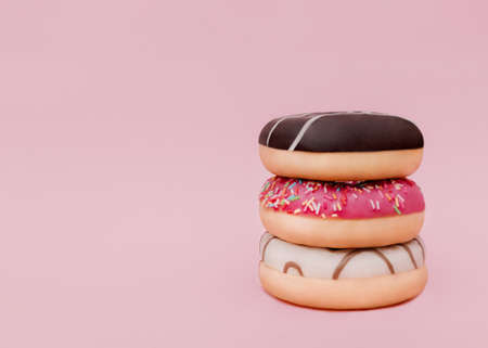 donuts. Photo with copy space. Mixed colorful donuts with sprinkles on pink backgroundの写真素材