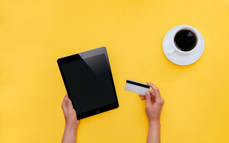 online shopping. Photo in minimal style. Woman holding tablet and credit card while sitting at deskの写真素材